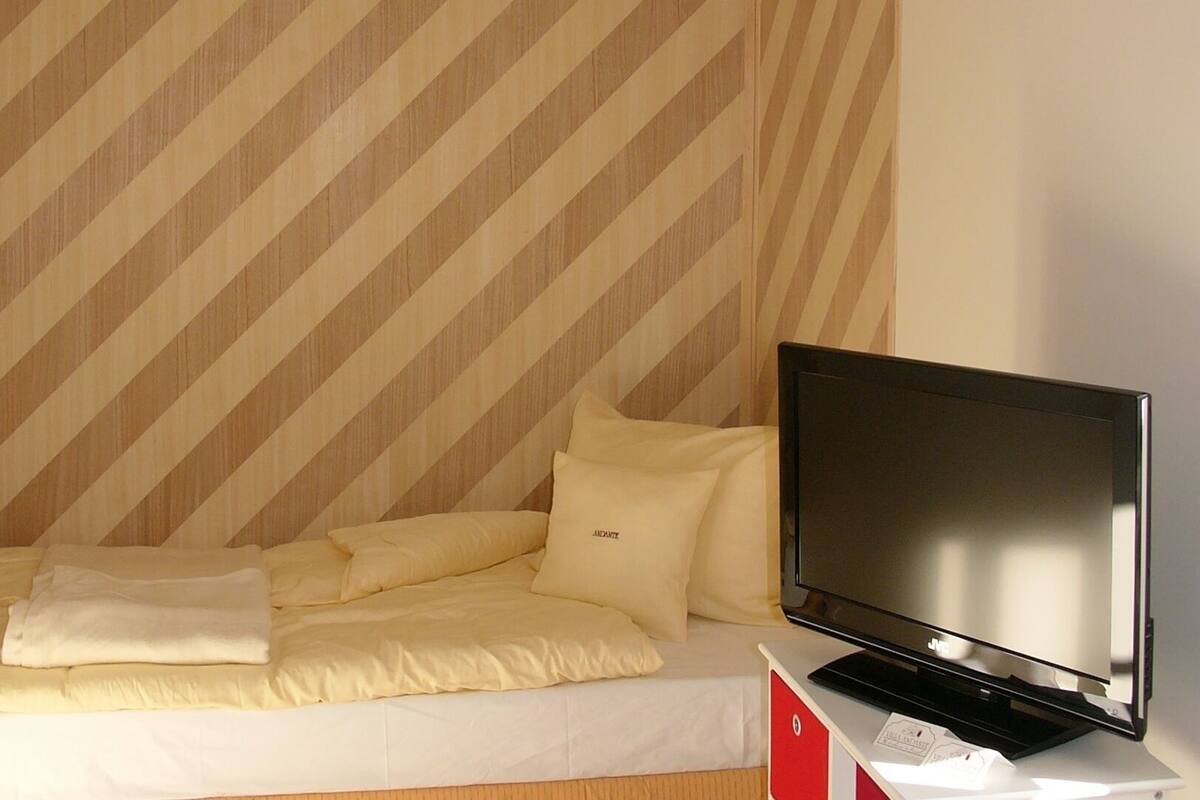Ein Hotelzimmer mit einem Bett, einem Fernseher und einer gestreiften Wand.