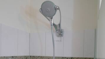 A showerhead with a flexible hose, mounted on a wall with white tiles.