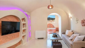Una sala moderna con televisión, sofá y mesa de centro. Hay chimenea, vistas al exterior y una lámpara de techo.