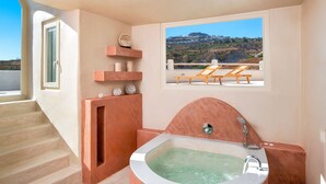 Un baño con una bañera independiente, un ventanal con vistas a una colina y un conjunto de escalones que conducen a otra habitación.