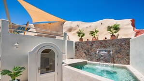 Zona de spa con hidromasaje, plantas en macetas y una pared de piedra.