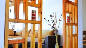 Une cloison en bois, avec un canapé et un vase rempli de branches séchées.
