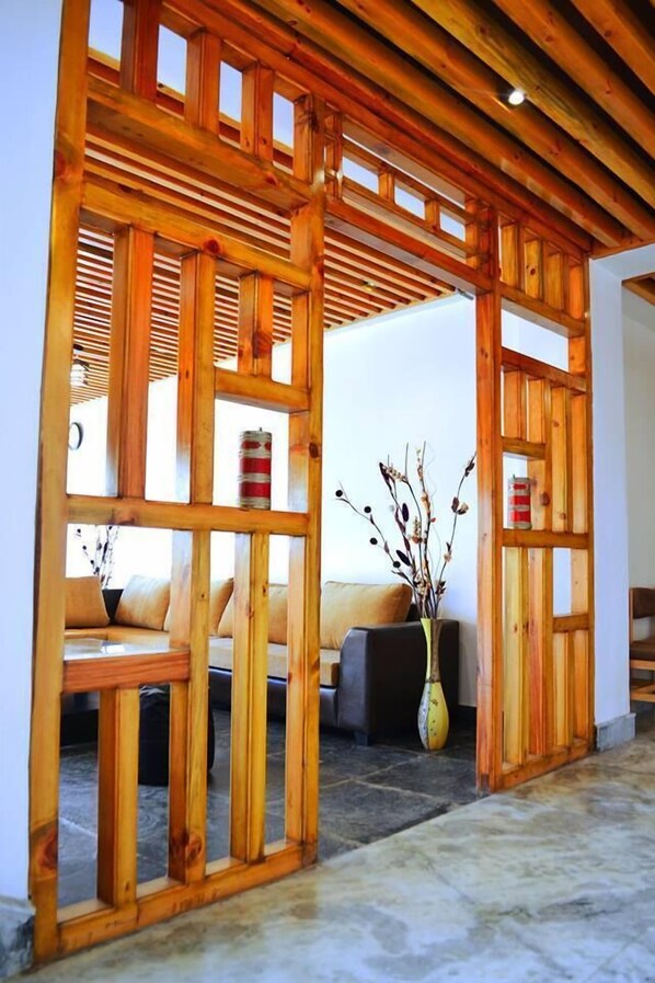A wooden partition with a sofa and a vase of dried branches.