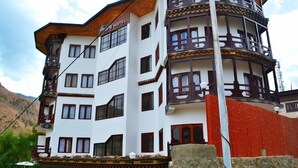 Un hôtel à plusieurs étages, doté d’une architecture traditionnelle, avec des balcons et un mur rouge qui attire l’attention.