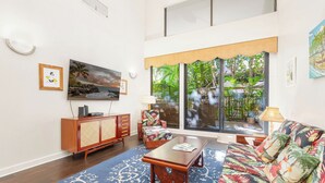 A spacious living room with a large window, a sofa, a coffee table, and a cabinet.