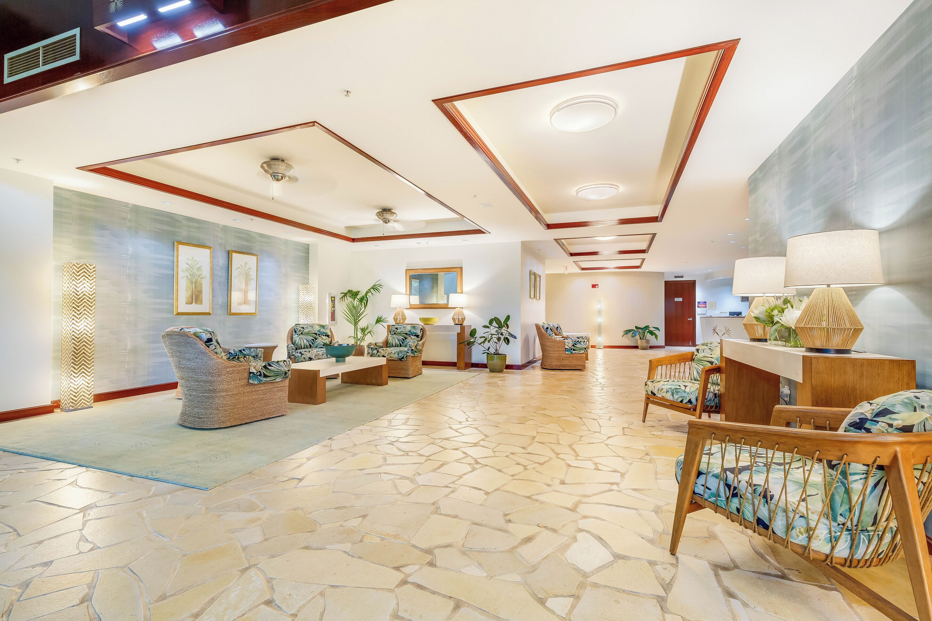 A spacious lobby with a stone floor, wicker furniture, and a reception desk.