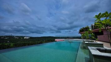 A swimming pool with a view of a hill and a building in the distance.