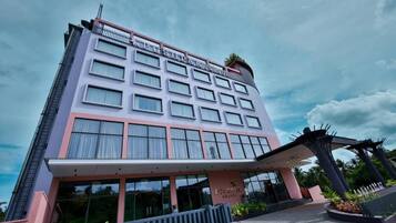 A multi-story hotel with a modern facade, large windows, and a covered entrance area.