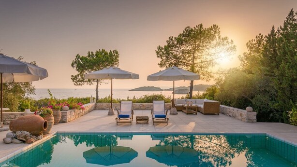 Área de piscina com espreguiçadeiras, guarda-sóis e vista para o mar.
