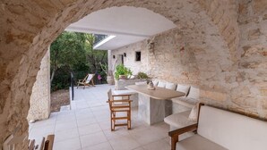 Um quarto com paredes de pedra, área de jantar com mesa e cadeiras, e um sofá.