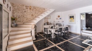 Escadaria que leva a uma sala de jantar com parede de pedra, lareira e piso de azulejos.