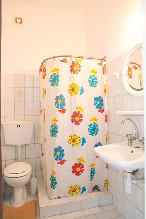 A bathroom with a toilet, sink, and shower curtain with a floral pattern. - Studios Evon Kalymnos (Kalymnos)