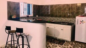 A compact kitchen with a black countertop, white cabinets, and a patterned backsplash. - Dar Aesha (Aghir)