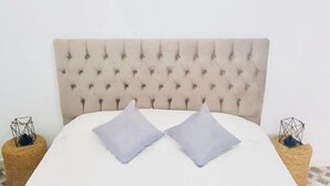 A bed with a tufted headboard, two pillows, and two nightstands with geometric lamps. - Dar Aesha (Aghir)