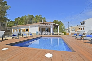 Una piscina con sillones de descanso y un área de patio.