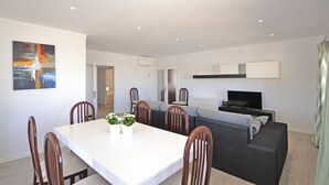 A modern living room with a dining table, chairs, a sofa, and a flat-screen TV. - Pinocha - House with private pool 300 meters from the beach in Mallorca (Can Picafort)
