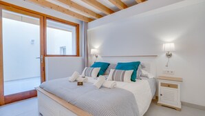 A bedroom with a bed, bedside tables, a window, and a door.