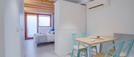 Una habitación moderna con techo de madera, una cama con vistas, una mesa con sillas y un equipo de aire acondicionado.