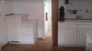 A small, compact kitchen with white cabinets and a countertop. - Baunaeck (Baunatal)