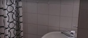 A bathroom with a tiled wall, a toilet, and a shower curtain with a circular pattern.