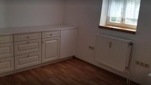 A room with a white dresser, a radiator, and a window with a white curtain. - Baunaeck (Baunatal)