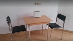 A small room with a wooden table and two chairs, a white toaster, and a power outlet on the wall. - Baunaeck (Baunatal)