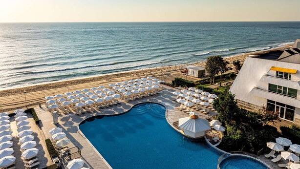 Un resort con piscina, sombrillas de playa y vista al océano.