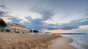Un hotel frente al mar con diseño moderno, que presenta un edificio grande con múltiples ventanales y techo plano.