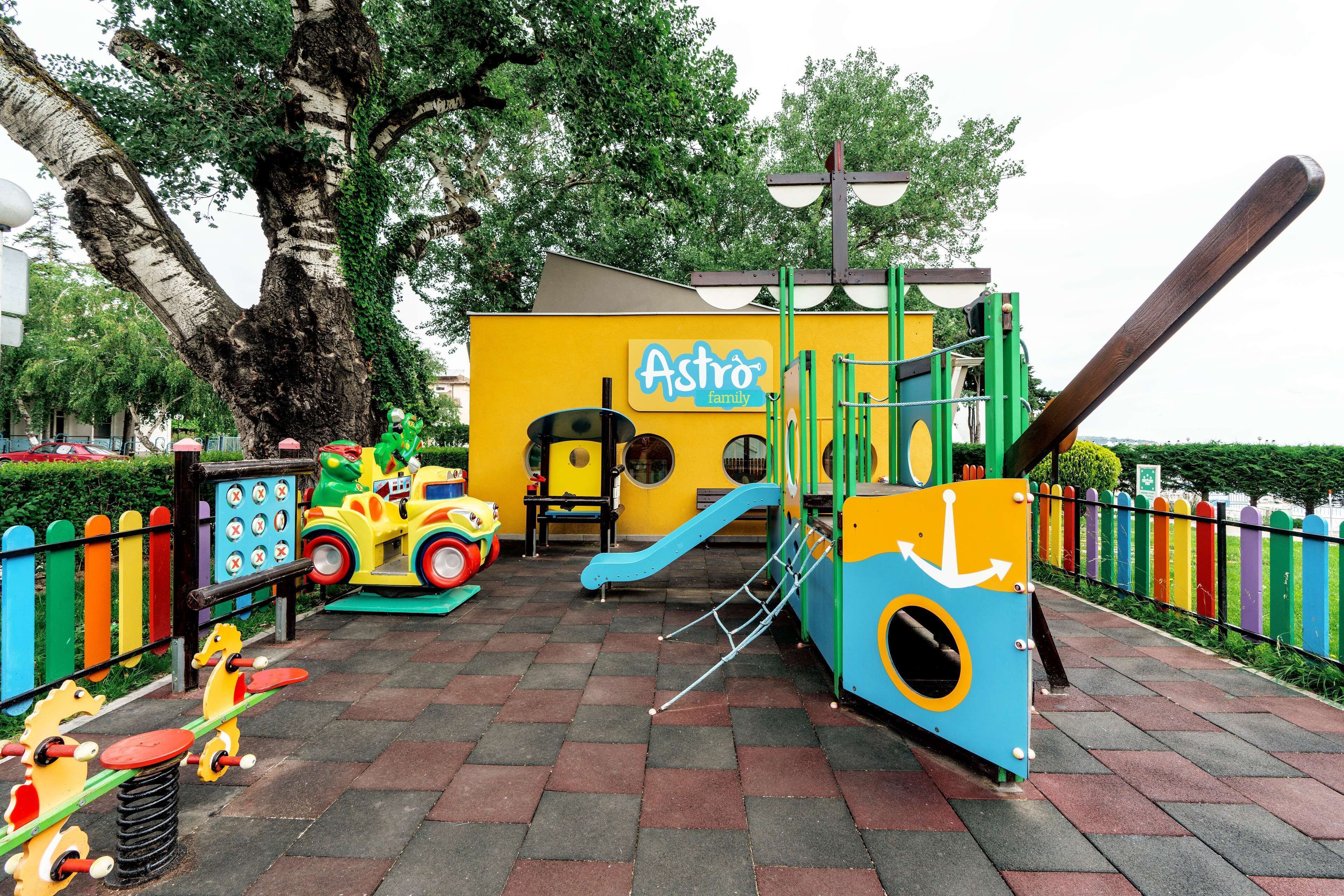 A playground with a slide, swings, and a yellow playhouse labeled "Astro family".