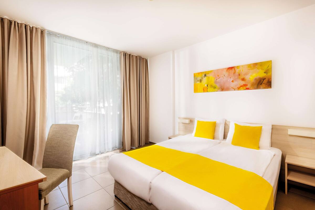A hotel room with a large bed, a desk, and a chair.