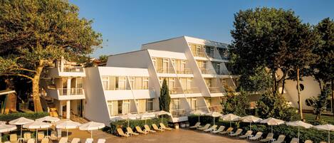 A modern hotel with a pool, multiple balconies, and sun loungers.