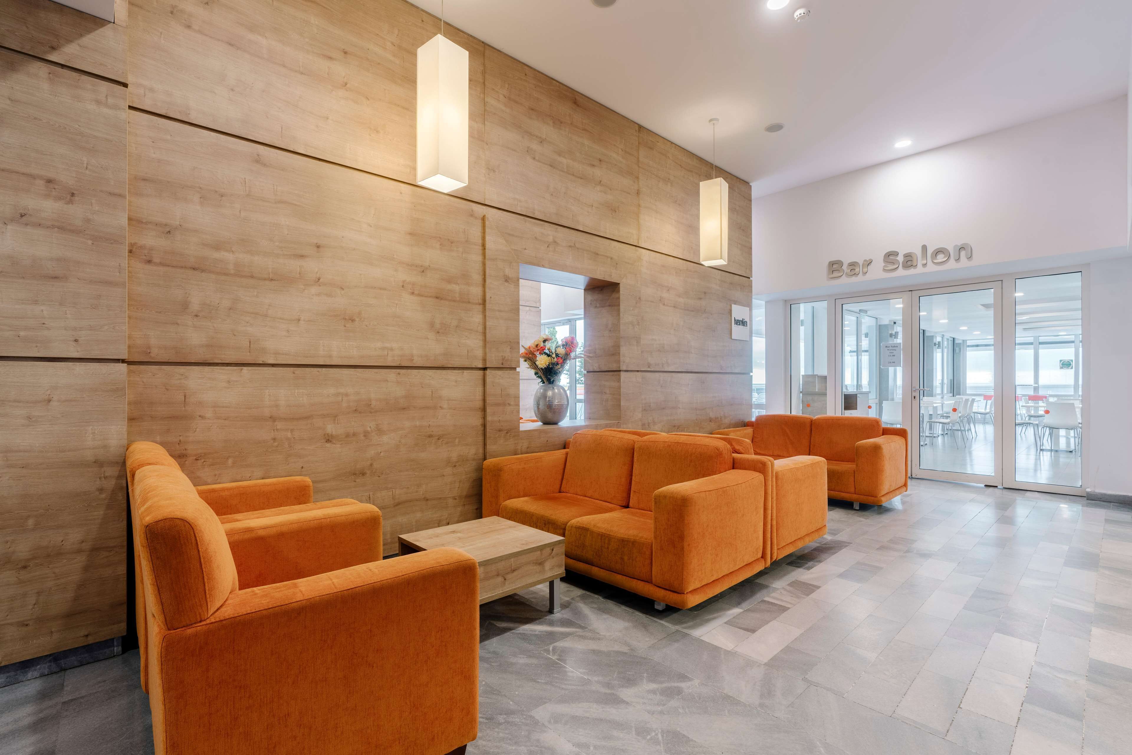 Un bar à l’ambiance moderne, avec des murs en bois, des sièges orange et une vue sur l’intérieur.