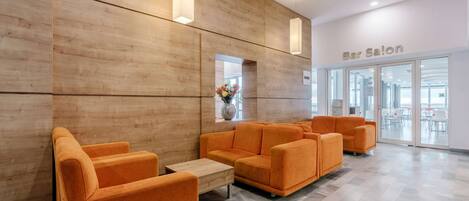Un bar à l’ambiance moderne, avec des murs en bois, des sièges orange et une vue sur l’intérieur.