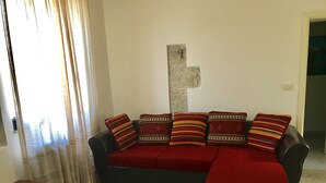 A living room with a dark-colored sofa, five patterned cushions, and a red throw blanket. - A holiday in unspoiled nature (Modica)