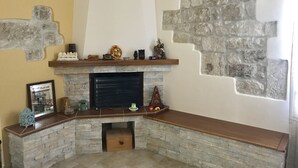 A stone fireplace with a mantel shelf, a framed picture, and a small decorative tree. - A holiday in unspoiled nature (Modica)