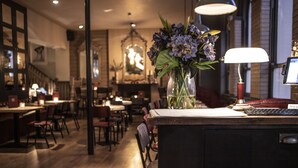 A bar area with a wooden counter, a vase of flowers, a lamp, and a computer monitor. - The Hayden Pub & Rooms (London)