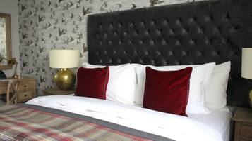 Ein Hotelzimmer mit einer geblümten Kopfteil, einer Karo-Bettdecke und roten sowie weißen Kissen.