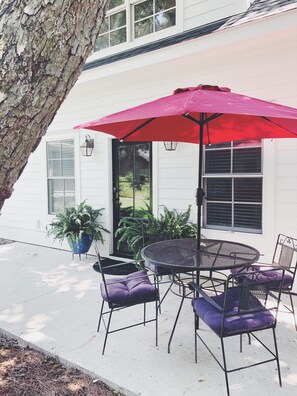 A patio with a round table and chairs, a red umbrella, and potted plants. - Charleston Guest House- Easy parking! Quiet, safe neighborhood! Close to Dwntn! (Charleston)