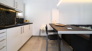 A modern kitchen with white cabinets, a black countertop, and a dining area with a table and chairs. - 45m2 homm Renovated Flat in Neos Kosmos Roumpesi str (Athens)