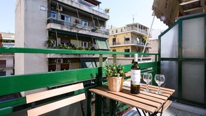 A balcony with a wooden table, a bottle of wine, and two glasses. - 45m2 homm Renovated Flat in Neos Kosmos Roumpesi str (Athens)