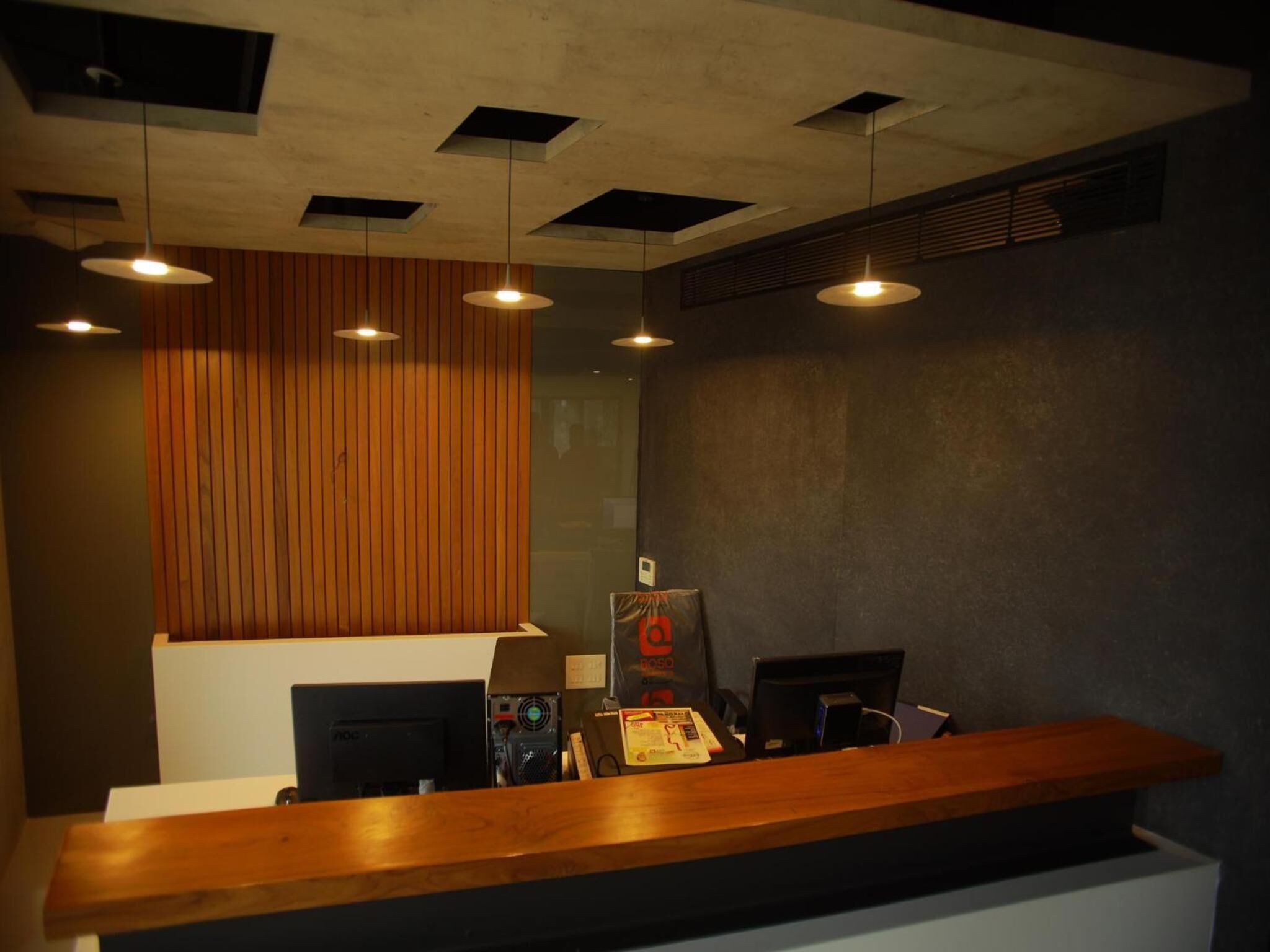 A reception desk with a wooden counter, multiple computer monitors, and a large poster on the wall.