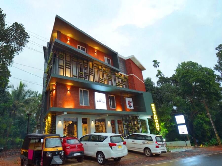 A multi-story building with a ground-level restaurant and upper-level rooms. There are cars parked in front.