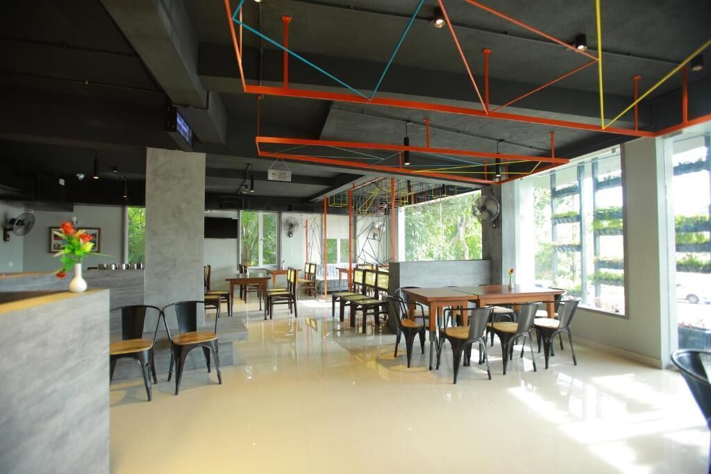 A modern interior with a central dining area, multiple tables, and chairs, surrounded by large windows.