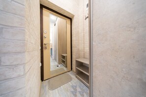 Enter a cozy space with a wooden door, a shelf unit, and a doormat at the entrance.
