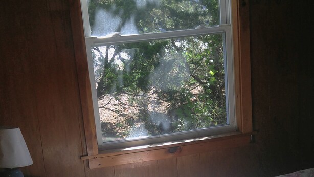 A bedroom with a window, a bed, and a nightstand with a lamp. - 2 bedroom cottages ocean views from property (Hampton)
