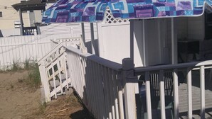 A beach house with a white exterior, a covered porch, and a sandy beach area. - 2 bedroom cottages ocean views from property (Hampton)