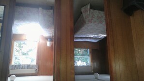 A room with wooden beams, a window with a view of trees, and a ceiling fan. - 2 bedroom cottages ocean views from property (Hampton)