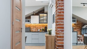 A modern kitchen with a brick wall, wooden cabinets, and a dining area with a table and chairs. - Barbakan Residence Old Town (Kraków)