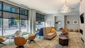 Un moderno vestíbulo de hotel con ventanas amplias, asientos cómodos, una araña y obras de arte en las paredes.