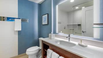 Un baño moderno con un inodoro blanco, un espejo grande y un lavabo blanco.